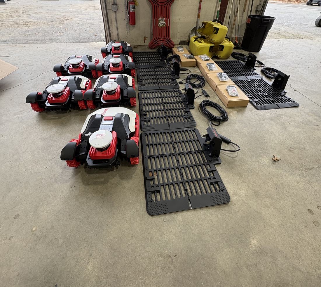 Six Kress RTK robots with charging docks, RTK antennas and cables staged on a shop floor